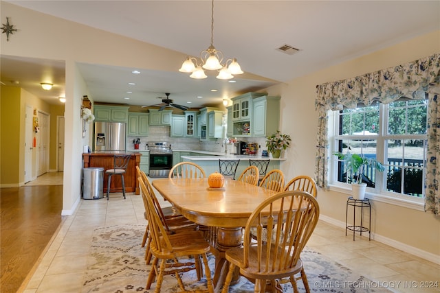 tiled dining space with ceiling fan with notable chandelier