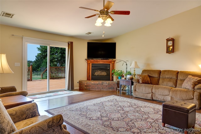 living room featuring wood-type flooring, a fireplace, and ceiling fan