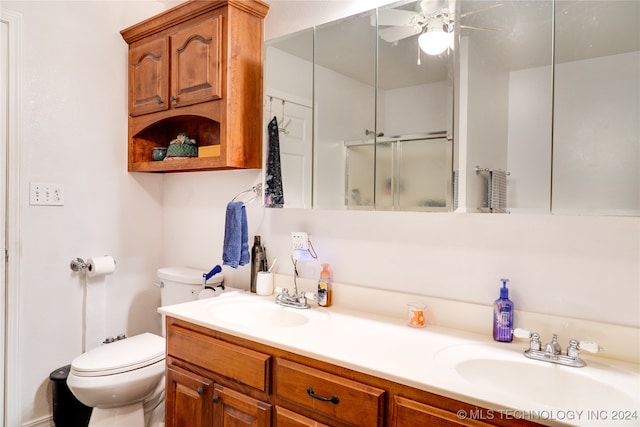 bathroom with ceiling fan, vanity, a shower with shower door, and toilet