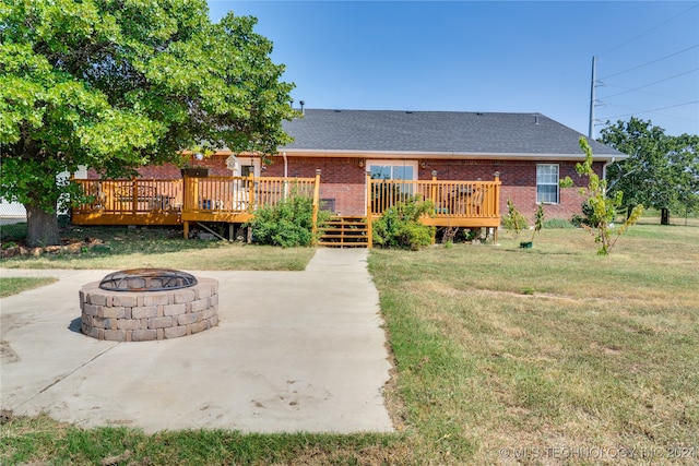 rear view of property with a fire pit, a wooden deck, and a lawn