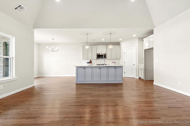 kitchen with decorative light fixtures, a kitchen island with sink, and dark hardwood / wood-style flooring