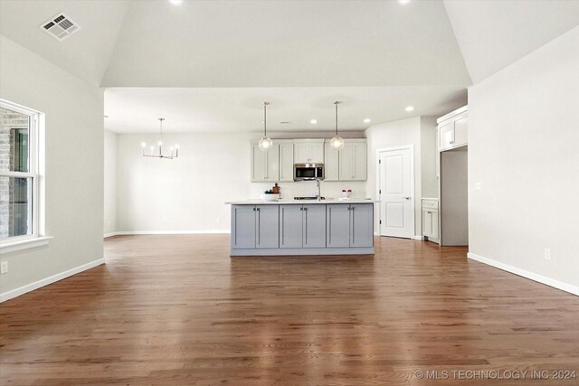 kitchen with decorative light fixtures, a kitchen island with sink, and dark hardwood / wood-style flooring