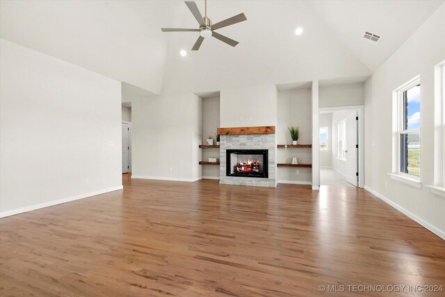 unfurnished living room with a stone fireplace, hardwood / wood-style floors, and high vaulted ceiling