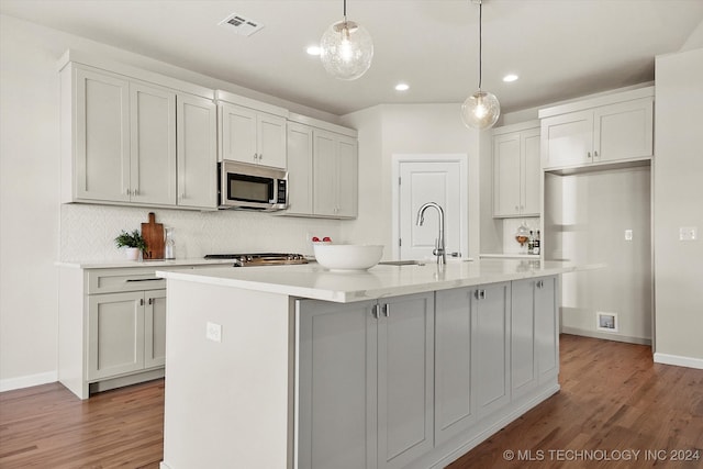 kitchen featuring an island with sink, dark hardwood / wood-style flooring, hanging light fixtures, and sink