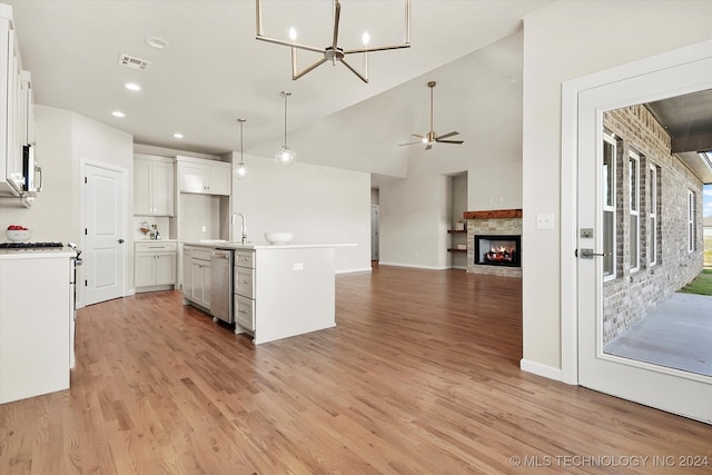 kitchen featuring white cabinetry, ceiling fan with notable chandelier, stainless steel appliances, light wood-type flooring, and a kitchen island with sink