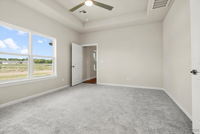 carpeted empty room featuring a raised ceiling and ceiling fan