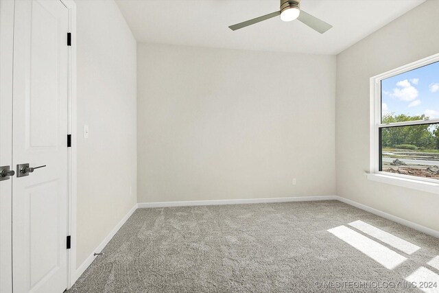 carpeted spare room with ceiling fan