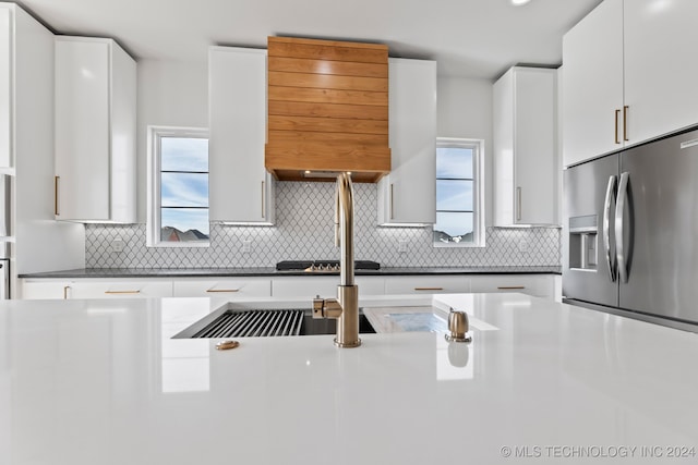 kitchen with a healthy amount of sunlight, tasteful backsplash, stainless steel appliances, and white cabinets