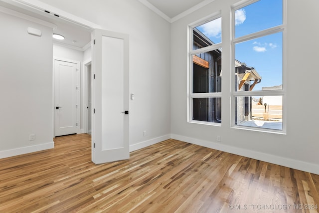 unfurnished room with light hardwood / wood-style floors and crown molding