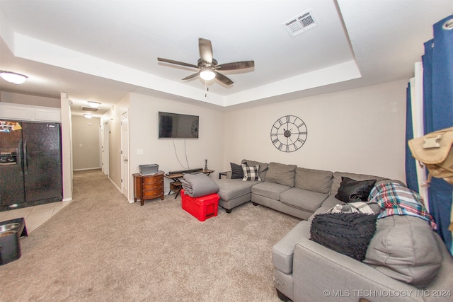 carpeted living room with a tray ceiling and ceiling fan