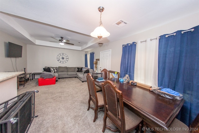 interior space with ceiling fan, a tray ceiling, and light carpet