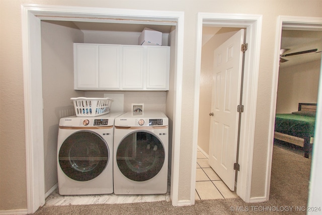 washroom with washing machine and dryer, light tile patterned flooring, and cabinets