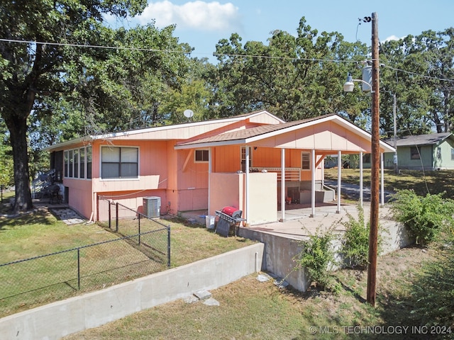 view of front of home with cooling unit, a patio area, and a front yard