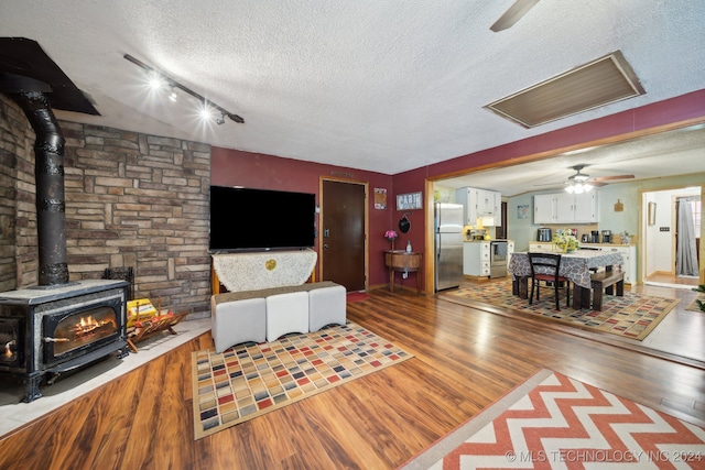 living room with a wood stove, a textured ceiling, hardwood / wood-style floors, and ceiling fan