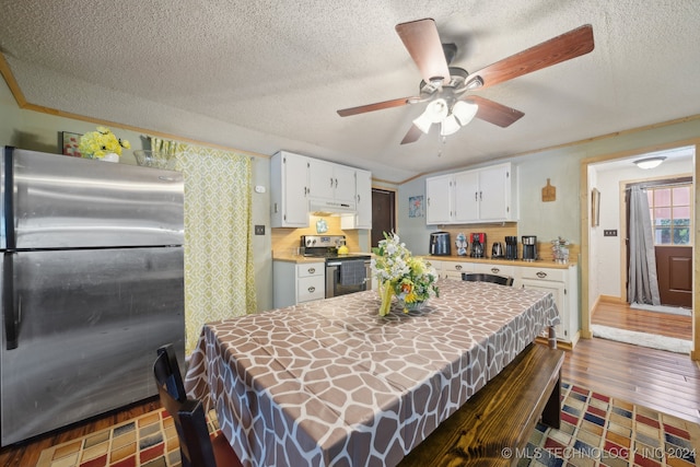 interior space with ceiling fan, a textured ceiling, stainless steel appliances, and dark wood-type flooring