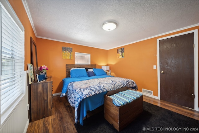 bedroom with a textured ceiling, crown molding, and dark wood-type flooring