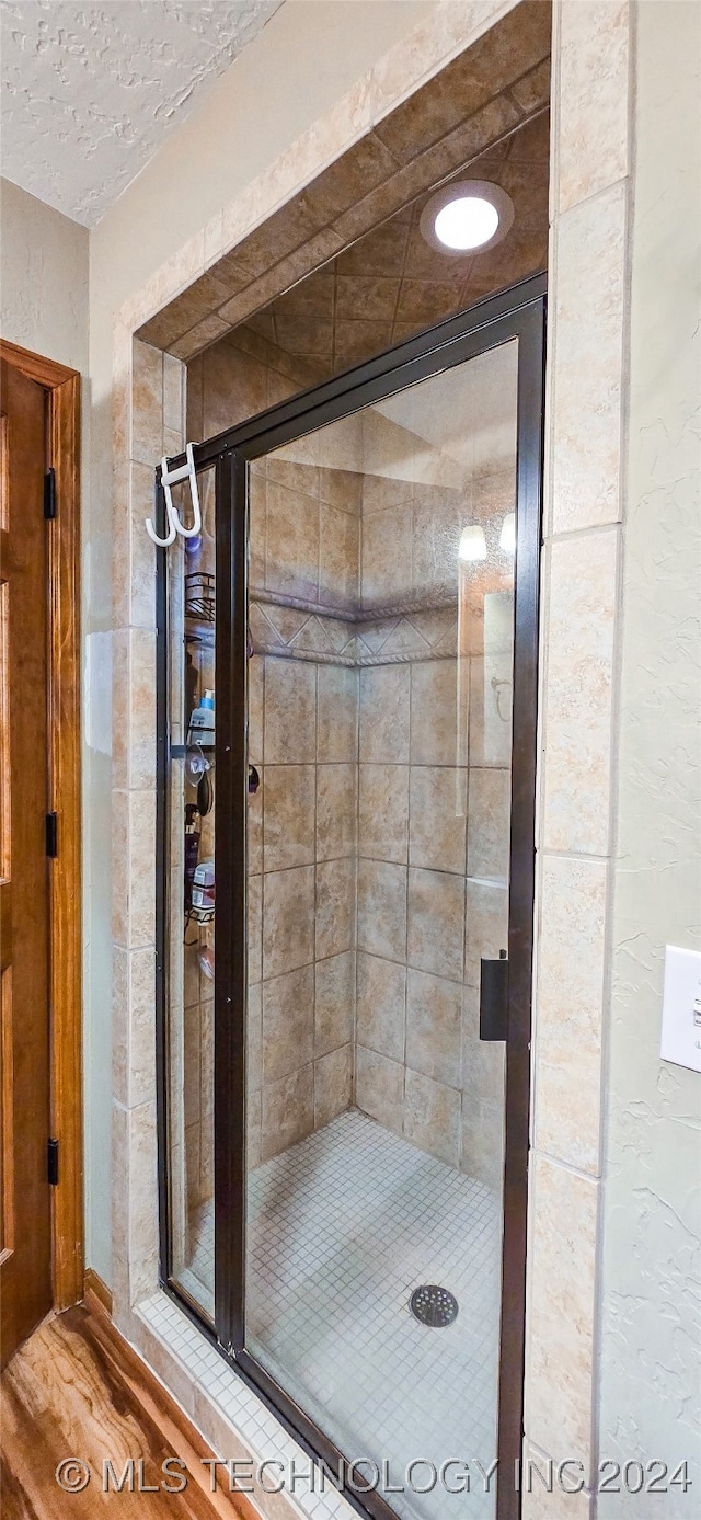 bathroom with hardwood / wood-style flooring and a shower with door