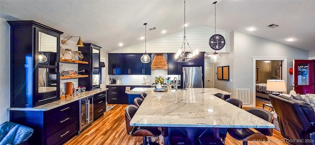 kitchen featuring a kitchen bar, stainless steel fridge, light hardwood / wood-style flooring, and pendant lighting