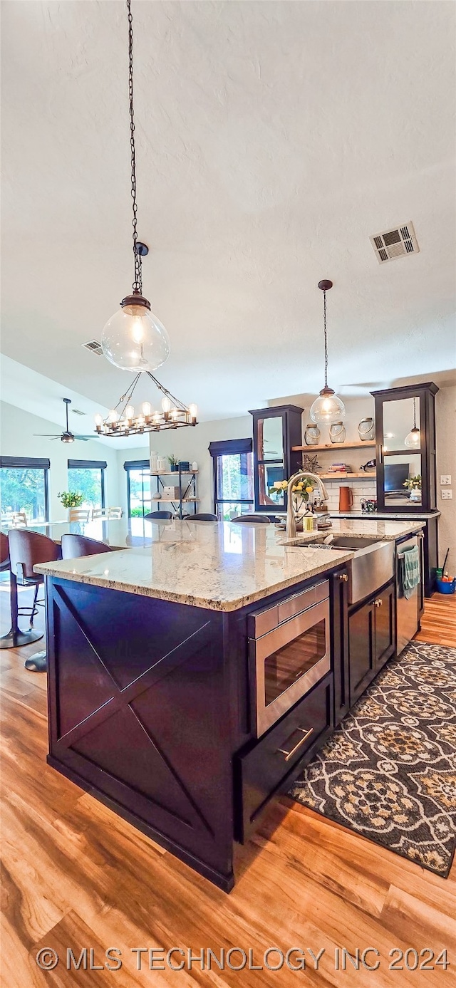 kitchen featuring pendant lighting, light wood-type flooring, and stainless steel microwave