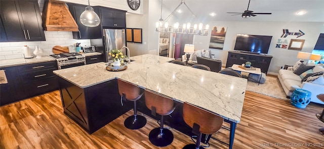 kitchen featuring a center island with sink, hanging light fixtures, and appliances with stainless steel finishes