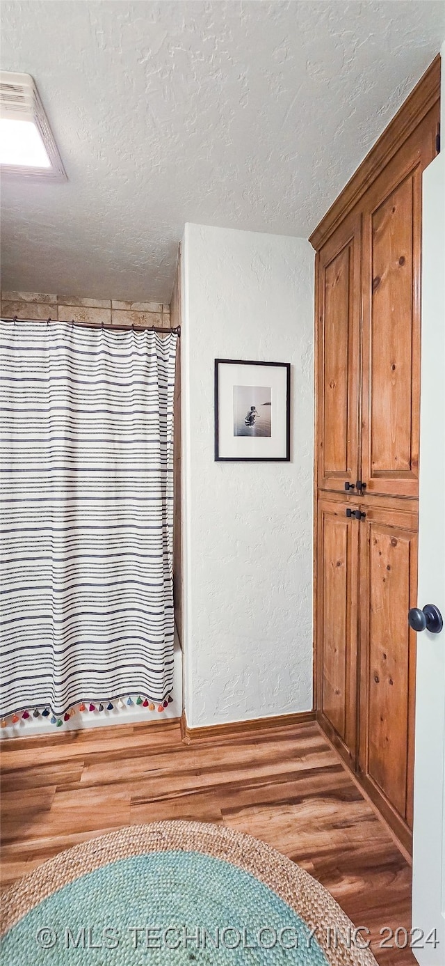 bathroom with wood-type flooring and a textured ceiling