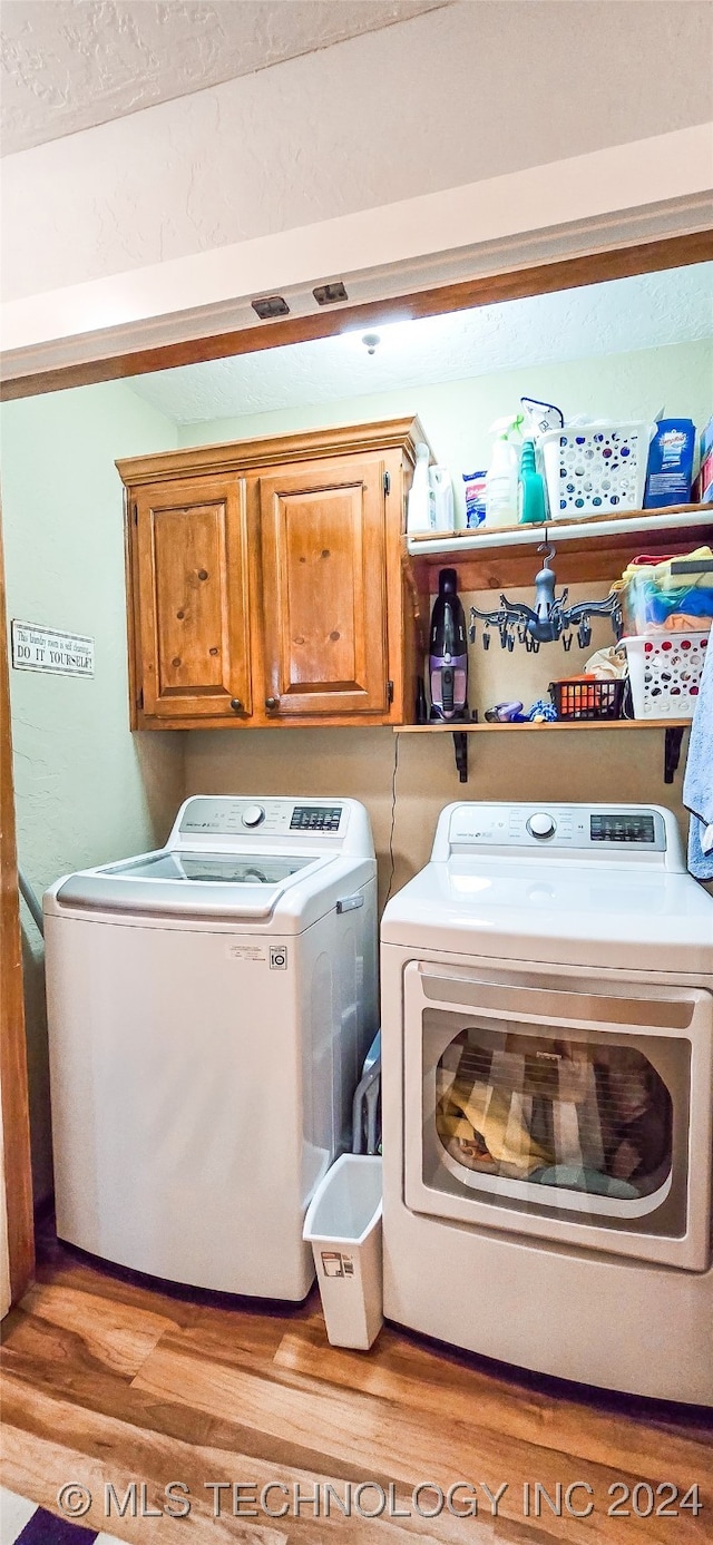 clothes washing area featuring separate washer and dryer, light hardwood / wood-style flooring, and cabinets