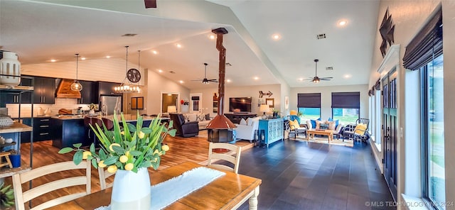 dining space with ceiling fan with notable chandelier, high vaulted ceiling, and dark wood-type flooring