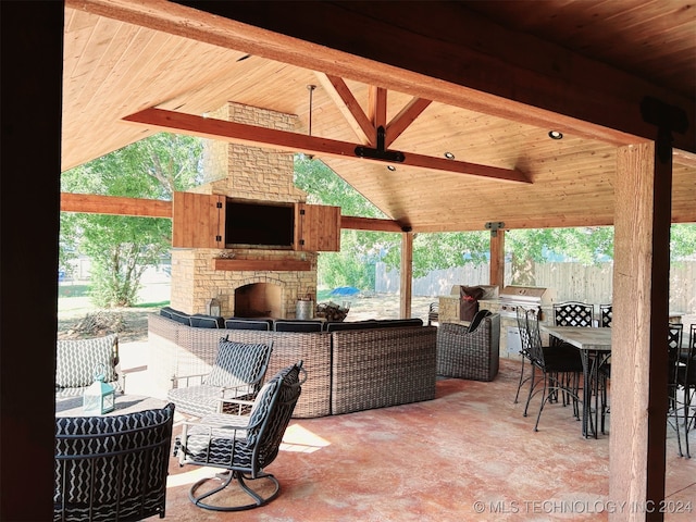 view of patio / terrace with an outdoor stone fireplace, a bar, and a gazebo