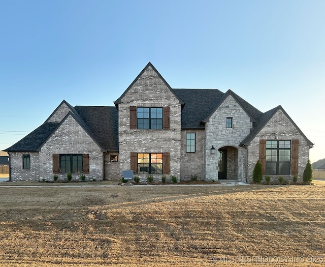 view of front of home featuring stone siding, brick siding, and roof with shingles