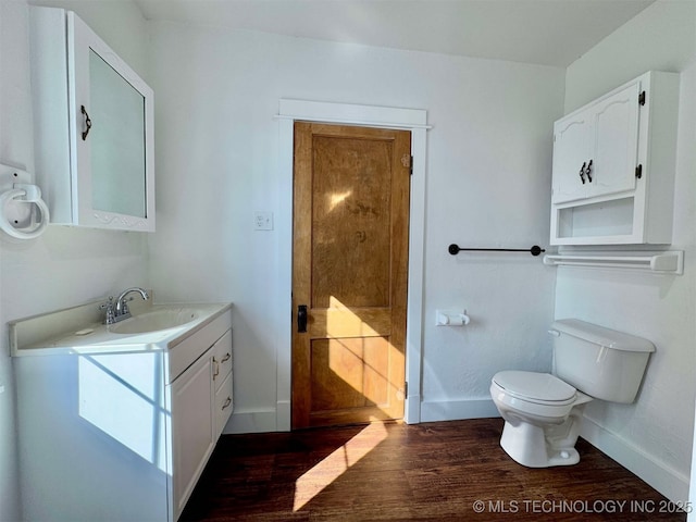 bathroom with wood-type flooring, vanity, and toilet