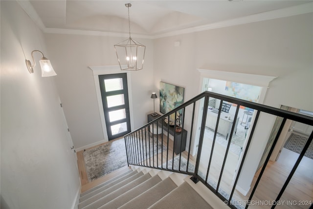 stairway with crown molding, an inviting chandelier, and hardwood / wood-style flooring