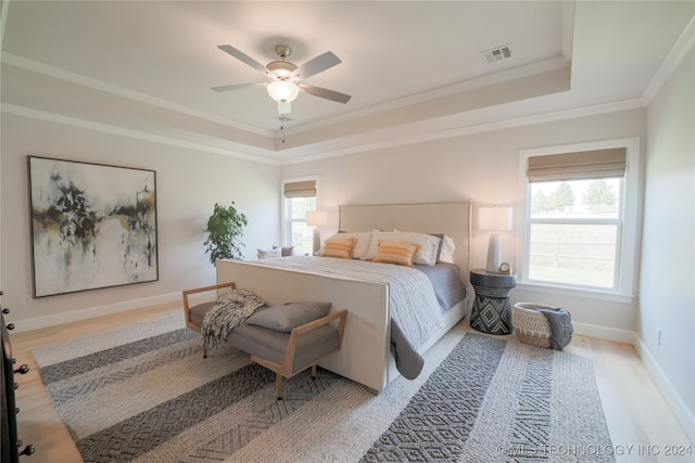 bedroom featuring ceiling fan, light hardwood / wood-style flooring, a raised ceiling, and ornamental molding