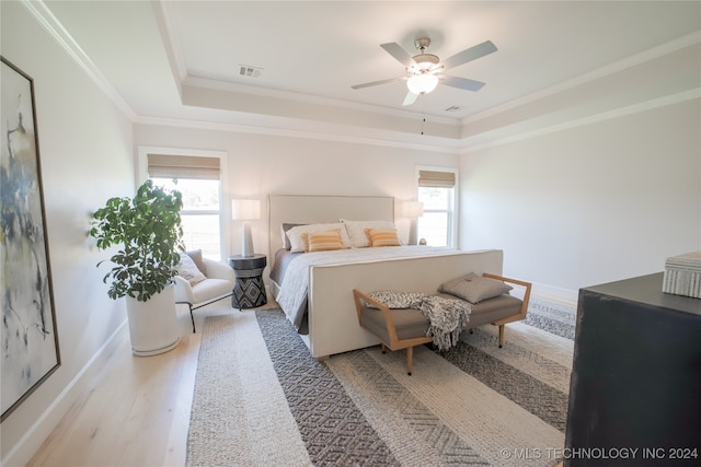 bedroom with light wood-type flooring, crown molding, a tray ceiling, and ceiling fan