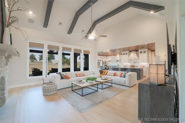 living room with light wood-type flooring, a fireplace, ceiling fan, and high vaulted ceiling