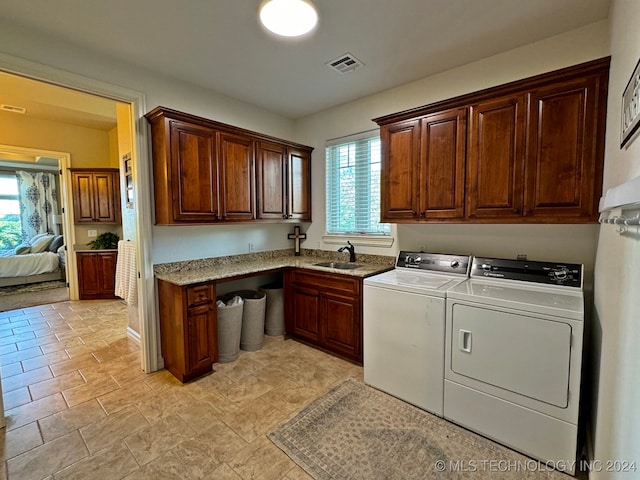 clothes washing area with washer and clothes dryer, sink, and cabinets