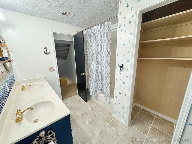 bathroom with a textured ceiling, a sink, visible vents, and tile patterned floors