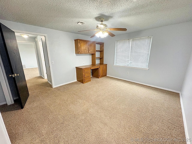 interior space featuring a ceiling fan, light carpet, a textured ceiling, and baseboards