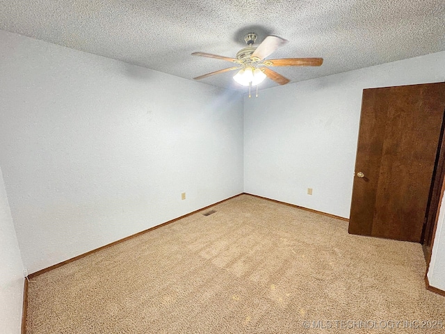 empty room featuring carpet, ceiling fan, a textured ceiling, and baseboards