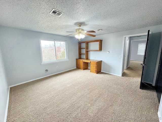 unfurnished bedroom featuring light carpet, a textured ceiling, visible vents, and baseboards