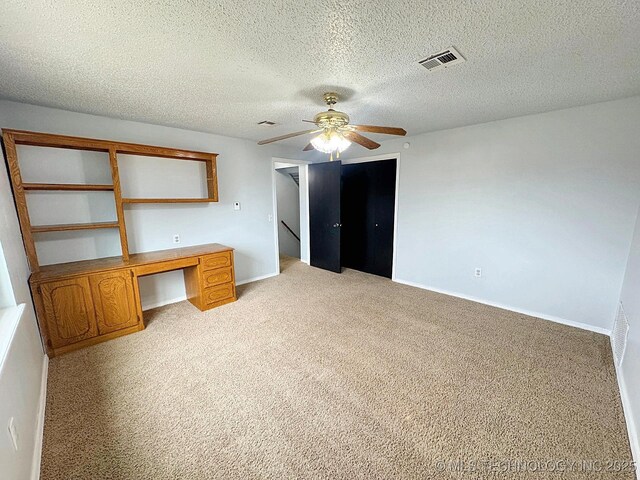 unfurnished bedroom featuring light colored carpet, visible vents, a ceiling fan, a textured ceiling, and baseboards