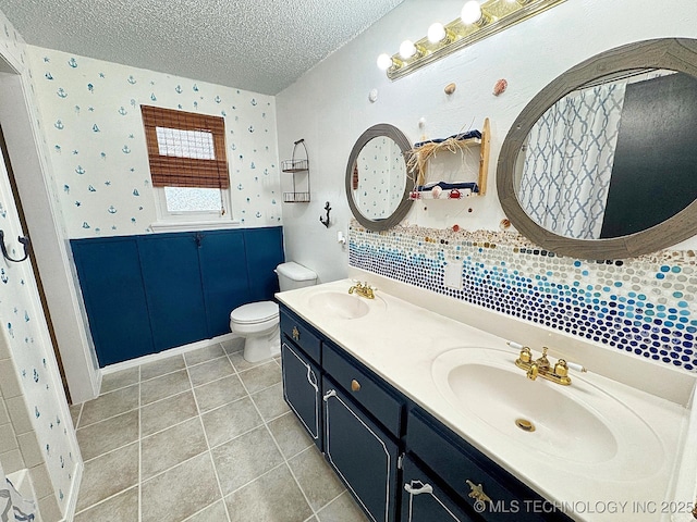 full bath with a textured ceiling, wainscoting, a sink, and toilet