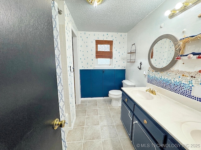 bathroom featuring double vanity, toilet, tile patterned floors, a textured ceiling, and a sink