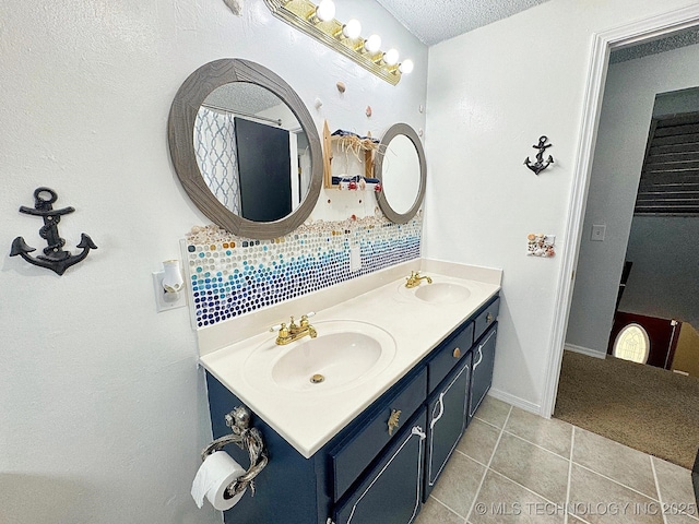 full bathroom with a textured ceiling, double vanity, tile patterned flooring, and a sink