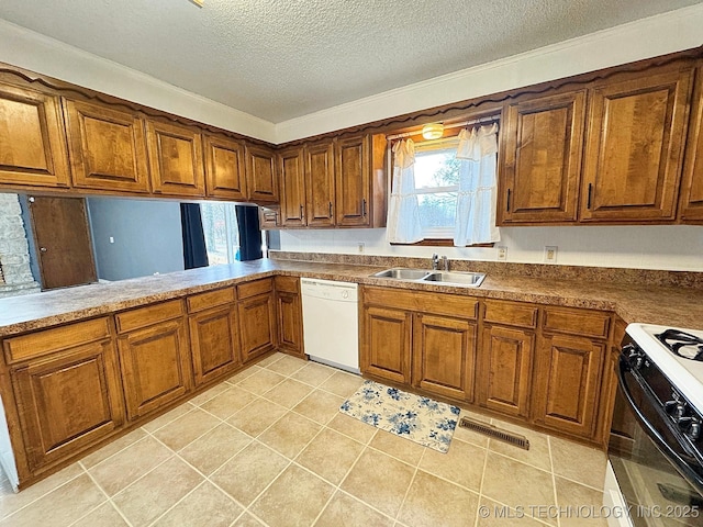 kitchen featuring white dishwasher, a sink, visible vents, brown cabinets, and gas range oven