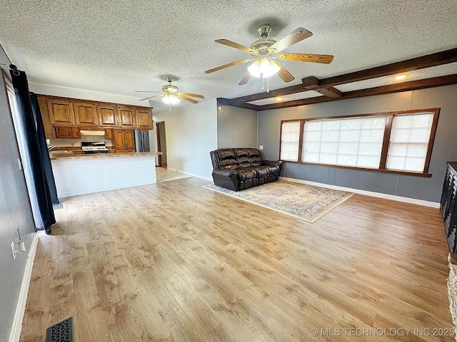 unfurnished living room with light wood-type flooring, beam ceiling, baseboards, and a textured ceiling