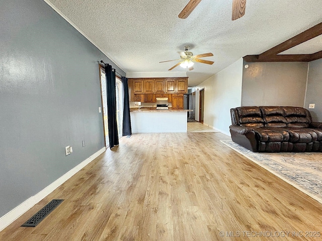 unfurnished living room with visible vents, ceiling fan, a textured ceiling, light wood-type flooring, and baseboards