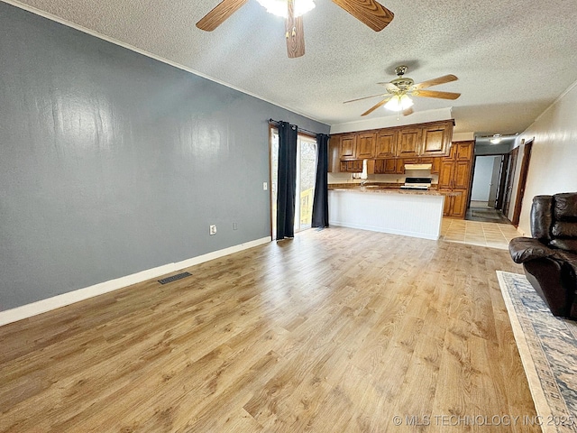 unfurnished living room featuring a textured ceiling, baseboards, visible vents, and light wood-style floors