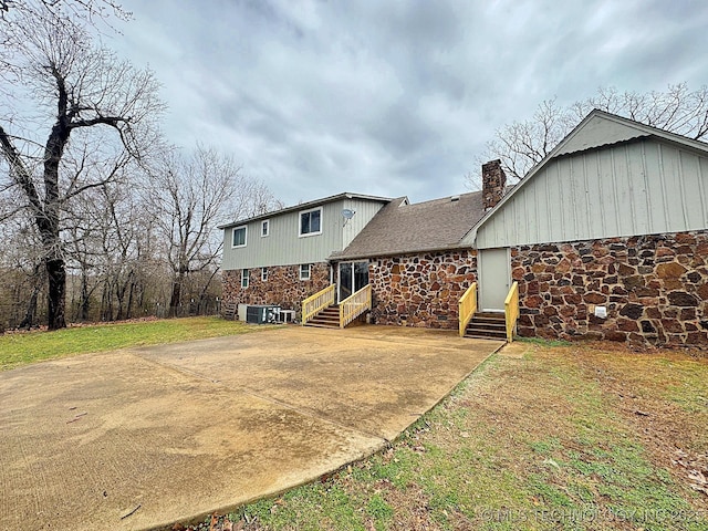 back of property with entry steps, a shingled roof, and a chimney