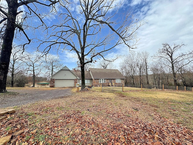 view of front of property with a garage, brick siding, gravel driveway, and fence