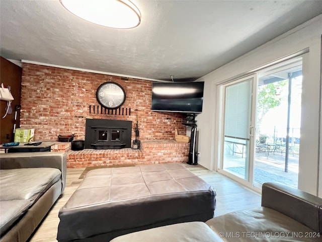 living room featuring brick wall, light wood-type flooring, a fireplace, and a wood stove